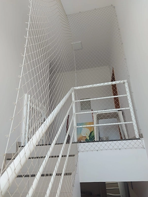 uma escada com corrimão branco, protegida com uma rede de proteção