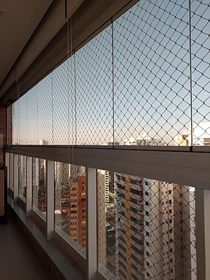 imagem de uma varanda, protegida com rede de proteção, com o por do sol, ao fundo